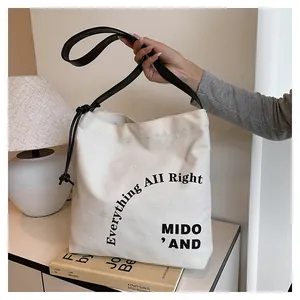 Dettaglio della borsa tote in tela con manici in pelle nera e decoro coulisse