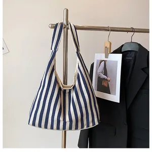 Sac fourre-tout en toile à rayures bleues et blanches suspendu à un support de métal
