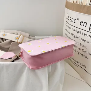 Detail of pink crossbody bag with daisy embroidery and golden metal buckle hardware