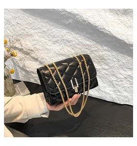Detail of black quilted leather shoulder bag with gold chain strap and metal lock