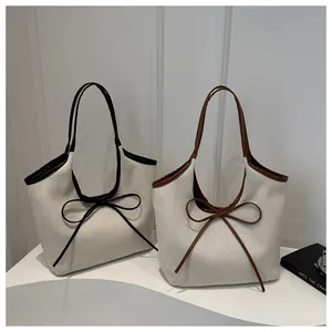 Detail of canvas tote bags with leather trim and decorative ribbon bows in two colors