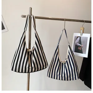 Gros plan de sacs cabas en toile à rayures noires et bleues sur un support d'exposition