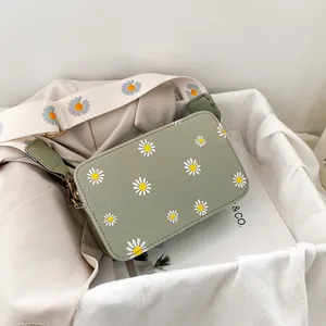 Detail of pea green crossbody bag with daisy prints and wide canvas shoulder strap