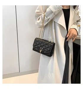 Detail of black quilted crossbody bag featuring gold chain strap and metal lock closure