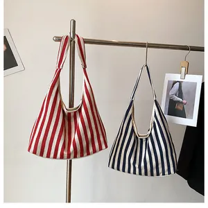 Gros plan de sacs cabas en toile à rayures rouges et bleues suspendus au présentoir