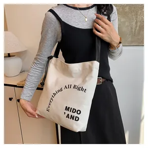 Dettaglio della borsa tote in tela con tracolla nera e stampa del testo 'Everything All Right'