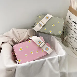 Detail of pink and green daisy crossbody bags with wide floral fabric straps