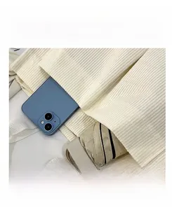 Detail of corduroy tote bag featuring front pocket with phone and folding umbrella