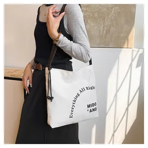 Dettaglio della borsa tote in tela bianca con coulisse nera e scritte grafiche stampate