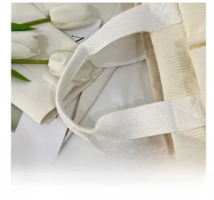 Close-up of cream corduroy tote bag featuring reinforced white woven handles and texture