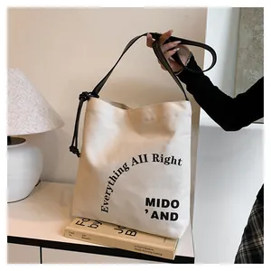 Dettaglio della borsa tote in tela beige con stampa grafica nera e nodi in pelle nera