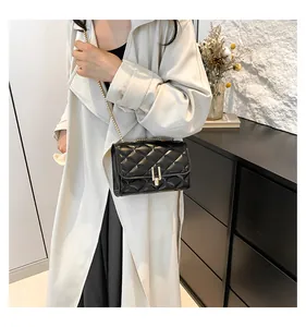 Detail view of black quilted crossbody bag with golden chain strap and metallic lock