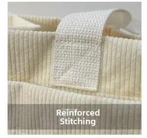 Macro detail of reinforced X-shaped stitching on the cream corduroy tote bag handle