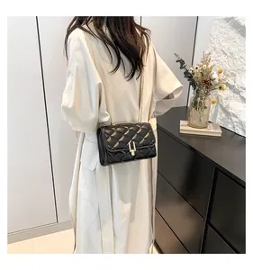 Close-up of black quilted chain bag with gold metal lock worn by a model from the side
