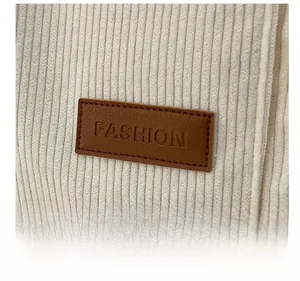 Detail of off-white corduroy fabric with brown leather patch embossed with Fashion