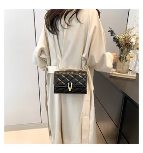 Detail of black quilted leather shoulder bag with gold chain strap and metal lock closure