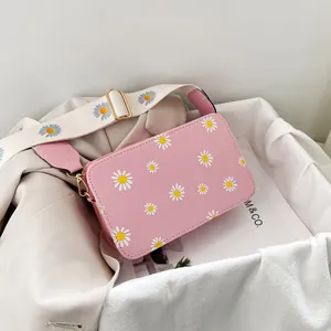 Detail view of pink PU leather crossbody bag with daisy prints and gold metal hardware