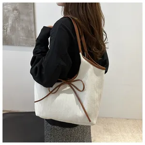 Close-up of cream canvas tote bag with brown leather trim and bow detailing