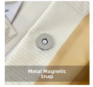 Macro detail of silver magnetic hardware buckle on a white corduroy tote bag