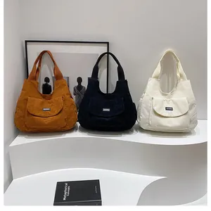 Three colors of corduroy tote bags shown on a display stand with a front pocket detail