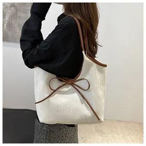 Close-up of herringbone canvas tote bag with leather bow and premium stitching details