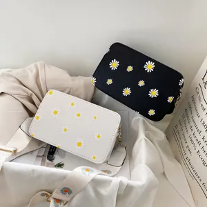 Detail of black and white square bags with daisy patterns and wide fabric straps