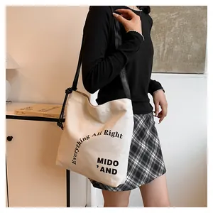 Dettaglio della borsa tote in tela con scritte nere e nodo in pelle elegante sul manico