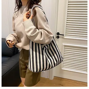 Grand sac cabas en toile à rayures noires et blanches porté par un mannequin