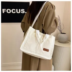 Detail view of corduroy tote bag with leather label and dual handle strap design