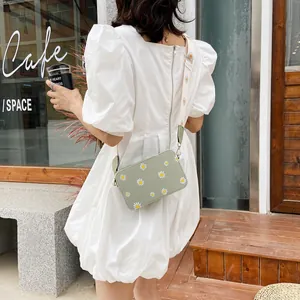 Detail of light green crossbody square bag featuring daisy prints and matching wide strap
