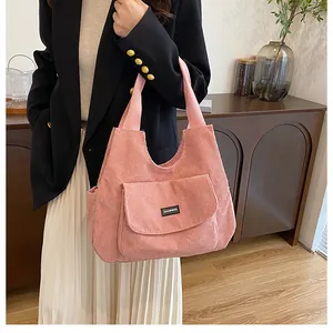 Detailed shot of pink corduroy tote bag showing front pocket flap and brand label texture