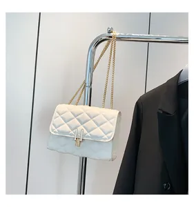 Detail of white quilted crossbody bag with golden chain strap and metallic lock closure