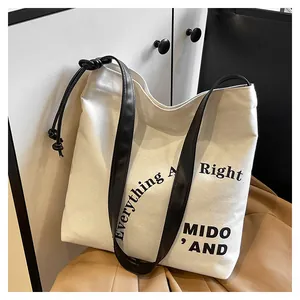 Dettaglio della borsa tote in tela bianca con manici neri e stampa di testo alla moda