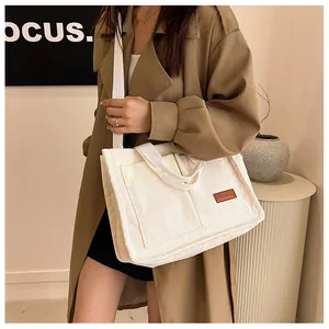 Detail view of large corduroy tote bag with dual handles and fashion logo patch