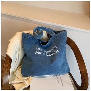 Close-up of denim tote bag with Less Mondays More Sundays white embroidery detail