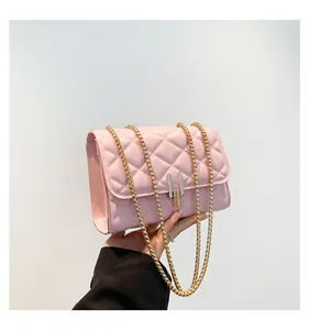 Close-up of pink quilted crossbody bag featuring a golden ball chain and U-shaped lock