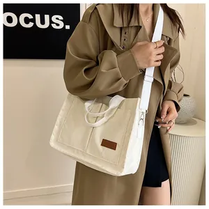Detail of off-white corduroy tote bag showing front pocket and brown faux leather patch