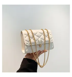 Close-up of white quilted handbag with diamond pattern and gold chain strap