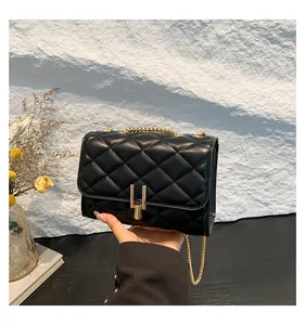 Close-up of black quilted leather texture with elegant gold U-shaped metal buckle and chain