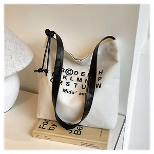 Dettaglio della borsa tote in tela crema con spalline in ecopelle nera e coulisse