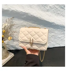 Close-up of beige quilted crossbody bag with gold metal lock and chain strap detail