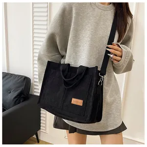 Detail of black corduroy tote bag showing 'FASHION' label and front large pocket