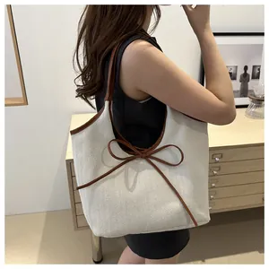 Canvas herringbone tote bag with brown leather trim shown on a model in a stylish interior