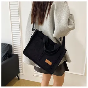 Detail of black corduroy tote bag showing 'FASHION' patch and wide shoulder straps