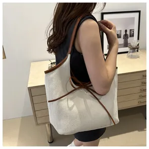 Close-up of beige herringbone canvas tote bag with brown leather bow and trim details