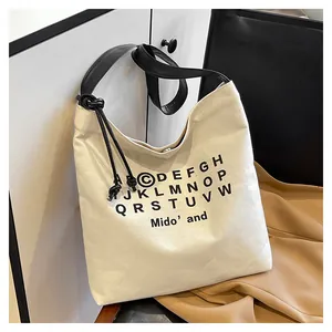 Dettaglio della borsa tote in tela crema con stampa di lettere nere e spallina annodata