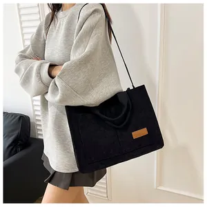 Detail of black corduroy tote bag with front pocket and faux leather fashion patch