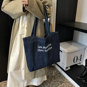 Retro denim tote bag with white embroidery shown on shoulder for a stylish casual look