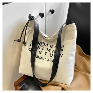 Primo piano della borsa tote in tela con manici in pelle e coulisse laterale decorativa