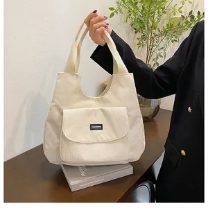 Detail of cream white corduroy tote bag featuring a front pocket and soft ribbed texture